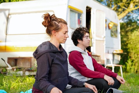 A lesbian couple meditates outdoors, enjoying a serene camping experience in their motorhome