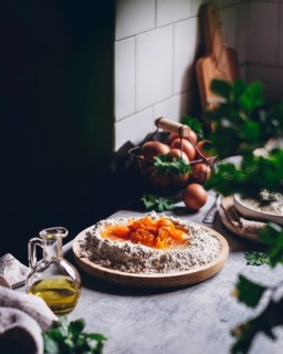 Rustic kitchen scene showcasing a mound of flour with eggs and vibrant yolks, alongside a glass jar