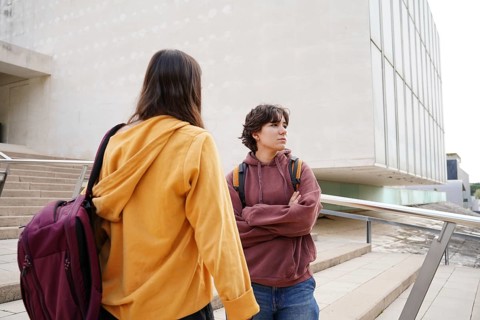 Two teenagers, one non-binary and the other female, engage in a thoughtful conversation on their