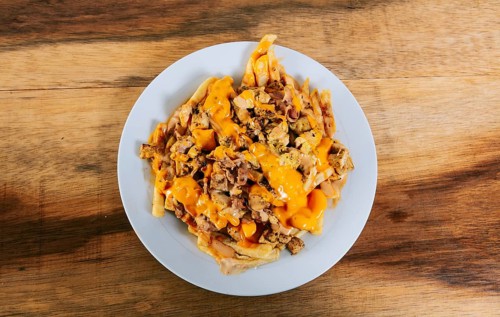 Top view of chicken nachos with melted cheese. Plate of chicken nachos with melted cheese on wooden