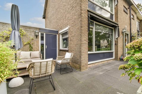 A stylish outdoor patio featuring comfortable seating setup against a modern building, surrounded