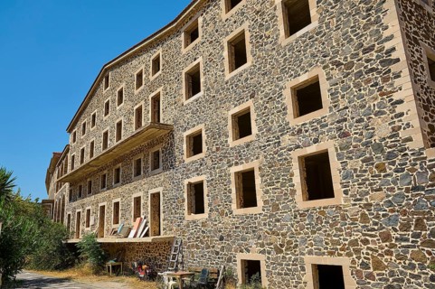 Abandoned building with numerous open windows in sunlight, ruins of a spa hotel, Pali village,