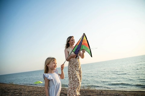 A mother and daughter enjoy a special moment with a colorful kite on an Italian beach, sharing
