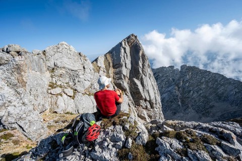 Mountaineer sitting on a rock and enjoying the view, mountain tour to the summit of the Hochkalter,