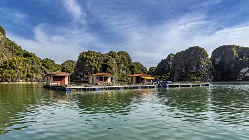 Houseboats on a lake surrounded by limestone cliffs under a blue sky, The floating villages in