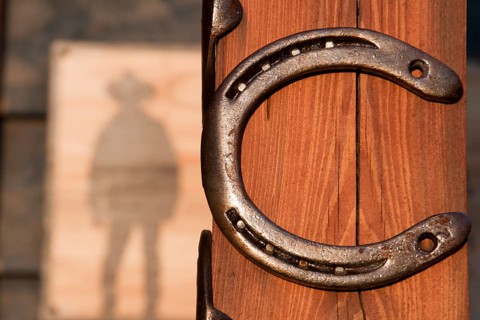 Horseshoes nailed to a pole behind an advertising sign, like for a cowboy saloon in the Wild West