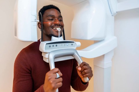 Patient smiles while undergoing a dental x ray scan in a modern dental clinic, demonstrating