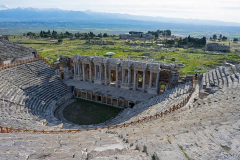View of an ancient theatre in a green landscape with mountains in the background, amphitheatre,