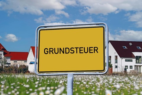 Symbolic image of property tax: Town sign with the inscription GRUNDSTEUER in front of a new