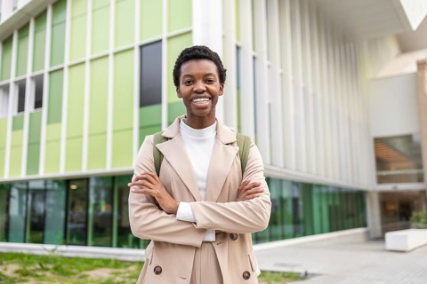 Confident black woman with short hair stands in front of a modern urban building, exuding