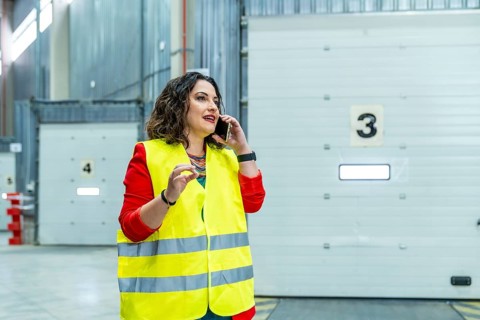 Woman talking to the mobile phone while working in a distribution warehouse