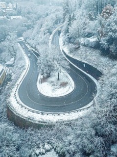 Snow-covered winding road surrounded by trees from a bird's eye view, Black Forest, Calw, Germany