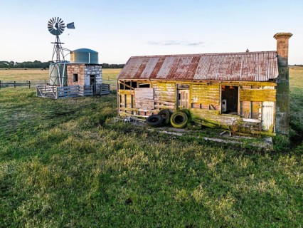 Weathered wooden farmhouse with a rusted roof, surrounded by grassy fields in Victoria, Australia.