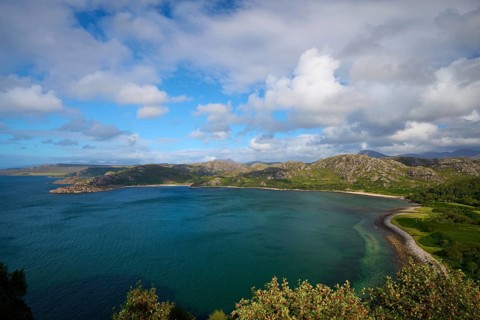 Panorama of coast and sea under cloudy sky connected by green landscape, Gruinard Beach, First