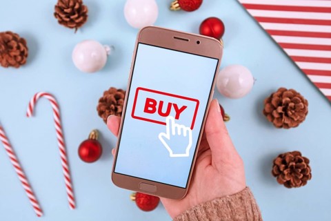 Concept for Christmas seasonal online shopping and sales with hand holding cell phone with Buy