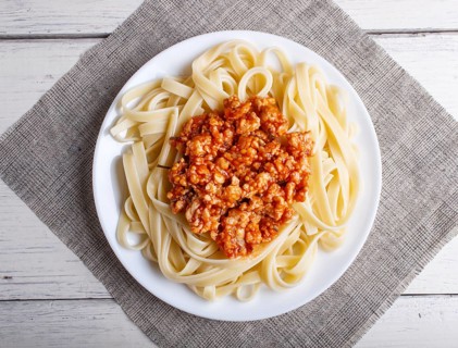 Fettuccine bolognese pasta with minced meat on white wooden background. top view, close up