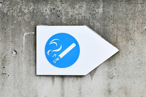 Germany, May 2025: White and blue arrow shaped sign with cigarette pointing towards designated