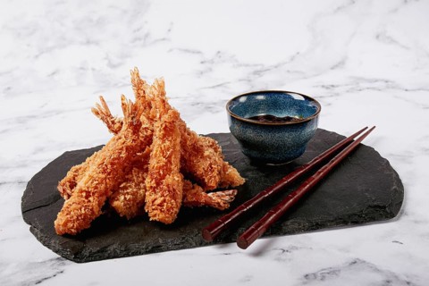 Shrimp in tempura, deep fried, on black slate, with sauce, light marble table, no people