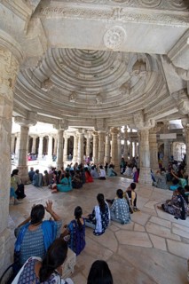 Indian woman praying between the white marble pillars in the Adinath temple in Ranakpur, Jain