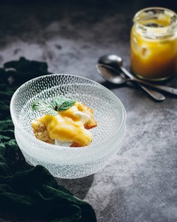 A delectable lemon curd cake, topped with a fresh mint leaf, served in an elegant glass dish.