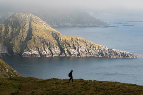 A hiker explores the stunning coastal mountains of Norway, emphasizing adventure and tranquility