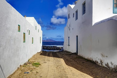 Narrow alleyway with sea views between white houses, Caleta de Famara Lanzarote