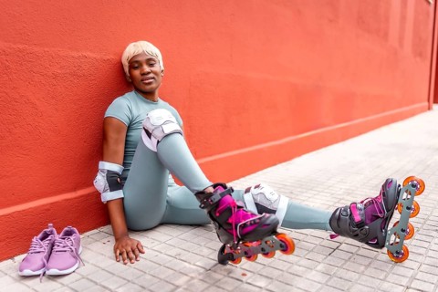 African urban woman sitting on the ground in the street wearing inline skates