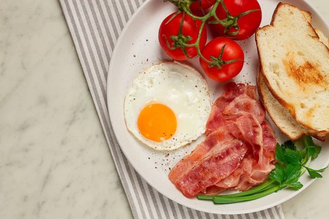 Breakfast, fried egg, bacon and bread, with cherry, on a light background, homemade, no people