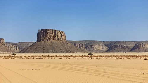 Imposing rock in a vast desert landscape under a blue sky, Lonely mountain formed by erosion in the