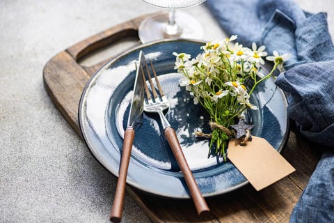 A charming arrangement of summer daisies rests elegantly on a blue ceramic plate with wooden