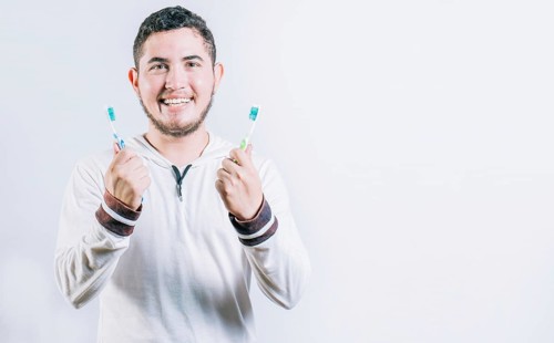 Teenager holding two toothbrushes isolated. Oral health concept. Toothbrush change concept