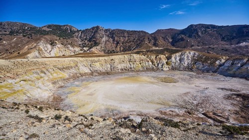 Large volcanic crater surrounded by mountains under a clear blue sky, volcanism, volcanic island,