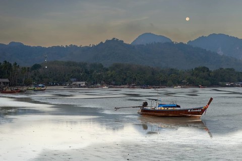 Before sunrise, longtail boats lie at low tide in the harbour at Sivalai Beach, Koh Mook Island,