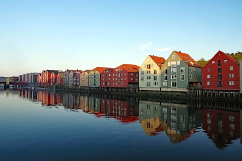 Row of colourful houses on the waterfront with clear reflection on the water surface under a clear
