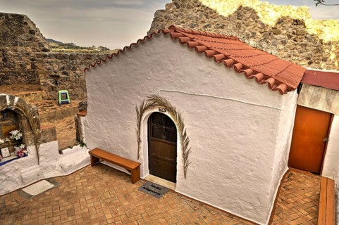 Small white chapel with tiled roof, embedded in old ruins, quiet atmosphere, natural stone,