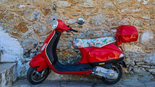 Vespa, Red retro scooter parked at an old stone wall, sunny day, Symi town, Symi, Dodecanese, Greek
