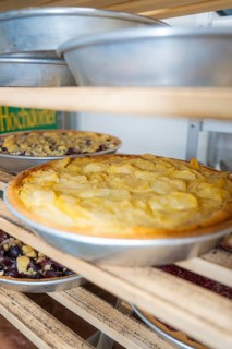 Different cakes placed on wooden shelves in a bakery, with warm light