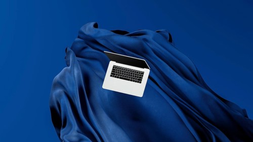 A sleek laptop is placed atop smooth fabric, showcasing its lightweight design against a rich blue