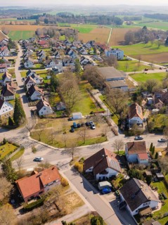 View from above of a cluster of houses in a village with surrounding streets and green