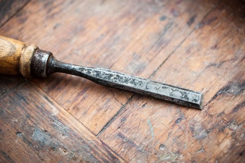 An old, worn chisel is lying on a scratched wooden workbench, detailed view, Hilden, Germany