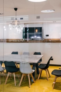 Minimalist meeting room with glass walls. Marble table, modern chairs, and a decorative geometric
