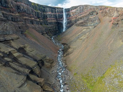 Waterfall Hengifoss, basaltic layers interwoven with red sedimentary layers, aerial view, Iceland