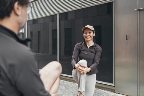 A couple enjoys stretching outdoors, preparing for a sports activity. Both are dressed in athletic