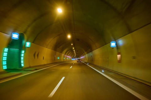 Illuminated motorway tunnel with several lights and signs, Switzerland