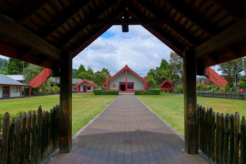 Traditional Maori village with red roofs and well-tended garden, New Zealand Maori Arts and Crafts