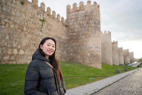 An Asian female tourist enjoys a scenic walk along the historic medieval walls of Avila, Spain. The