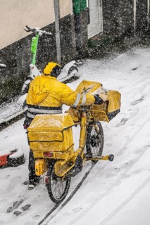 Winter weather, heavy snowfall, city centre traffic, postman with bicycle in the snow, Essen, North