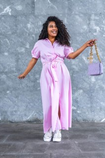 Vertical full length portrait of a happy elegant latin woman posing holding a chic purse against a