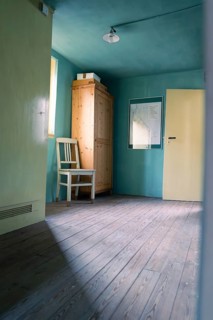 Simple room with wooden floor, green-painted walls, a chair and a cupboard, Calw Tannery Museum,