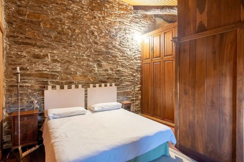 Charming bedroom featuring rustic stone walls and wooden furniture, located in a country house in